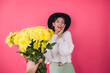 © Анастасия Каргаполов - Stylish woman in hat and casual white sweater on pink red background gets large bouquet of yellow flowers, spring mood, isolated space amazed excited surprised