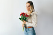 Attractive woman with a bouquet of red tulips. The woman is holding flowers and smiling. Festive concept of Valentine's Day or International Women's Day.