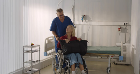 Male orderly pushing senior female patient being discharged from hospital in wheelchair