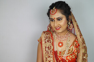 Indian bride with a bright makeup wearing a lehenga isolated on a white background