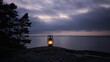 An old oil lantern with a lit fire stands on the rock outdoors at night. Cozy warm yellow light of an old kerosene lamp.