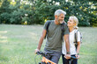 © PhotoAlto - Smiling mature couple with bicycle looking at each other in forest
