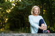© PhotoAlto - Smiling mature woman stretching her leg in forest