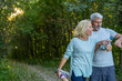 © PhotoAlto - Smiling mature couple checking their smart watches in forest