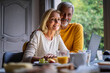 © PhotoAlto - Portrait of smiling mature couple using laptop at home
