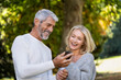 © PhotoAlto - Happy mature couple using smartphone in backyard