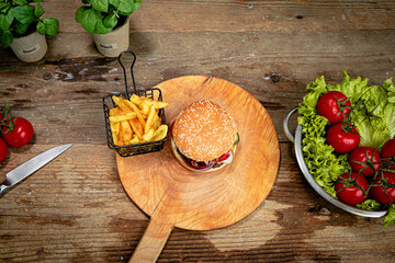 Sticker - Big delicious burger and french fries on a wooden board in the kitchen