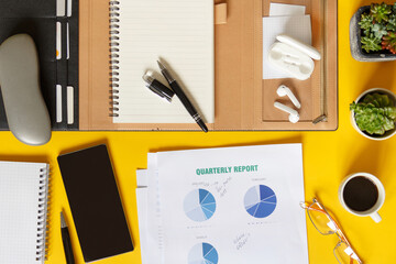 Agenda, Quarterly report and modern gadgets on a yellow office desk top view