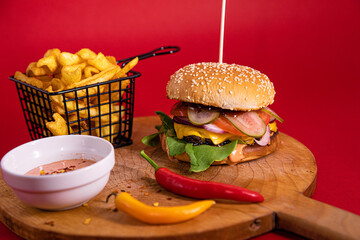 Poster - Big burger, french fries, Fry sauce and two chili peppers served on a wooden board