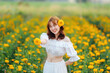 © Pornthiwa - Beautiful Asian woman wear white dress walking in marigold flowers garden.
