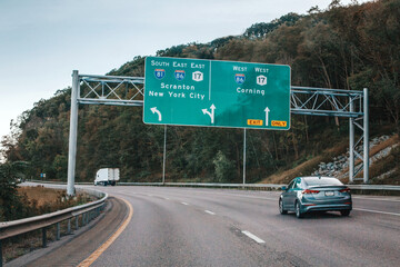 Cars on highway in American USA city country. Road to New York city. Green blue street signs to NY city. Empty road highway on summer day outdoor. Street road signs.