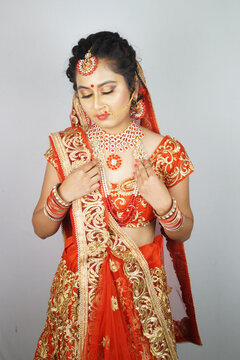 Gorgeous Indian bride with heavy makeup wearing traditional Indian bridal attire and posing