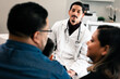 © Gerald R Carter Jr/Creative Flame - Hispanic family doctor consulting with patients in doctors office