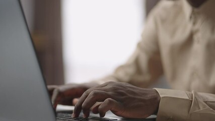 young afro-american man is using laptop with internet for working or educating, sending message and typing, view from hands to face