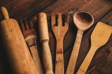 Wooden kitchen utensils on a wooden background. Handmade spoon. Pusher, spatula and spoon made of wood