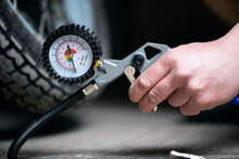 A Worker Is Inflating A Motorbike Wheel By The Car Tyre Inflating Gun Close Up.