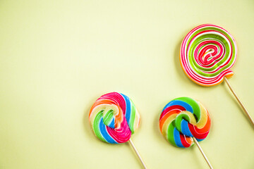 Canvas Print - Top view of three colorful lollypops on the light background with a copy space from the left