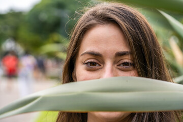 Portrait of a young Argentinian female smiling through the green leaves