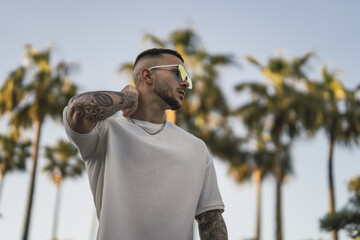 Sticker - Shallow focus shot of a handsome Spanish Caucasian man with tattoos and sunglasses posing outdoors