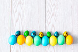 Fototapeta  - Colorful painted dye easter eggs lie in row on wooden white background with copy space, spring, easter concept, christian orthodox holiday