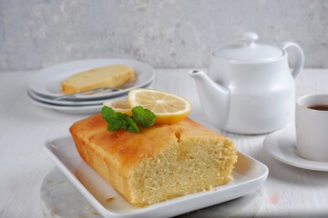 Wall Mural - Lemon pound cake with white teapot and a cup of coffee with blury background,white background