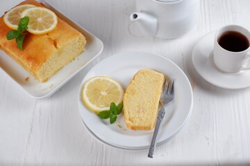 Wall Mural - Lemon pound cake with white teapot and a cup of coffee with blury background,white background