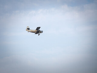 Old retro plane, a  vintage biplane with turbopropellers, flying, small, with a blue sky sunny background. It is a symbol of the beginning of aviation