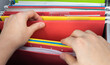 © Vipada - Closeup person's hand pick red hanging file folder from drawer.  Administration clerk finding paperwork from office storage. Corporate information record organization and database management concept.