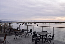 Outside Dining Area With Empty Chair And Tables With A Full View Of The Pier And Water
