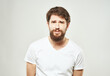 © SHOTPRIME STUDIO - Guy in a white T-shirt on a light background emotions sad face cropped view