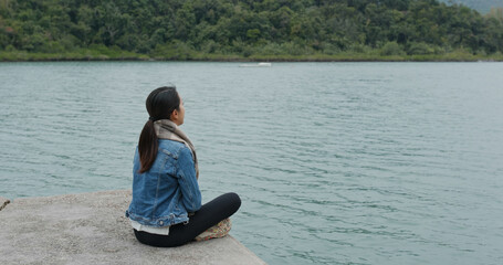 Wall Mural - Woman sit on pier dock and enjoy the sea view