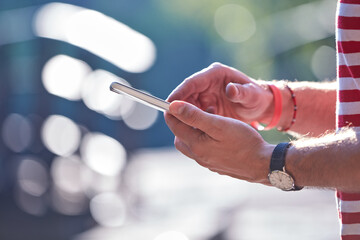 Wall Mural - Young adult man using modern smartphone in the park.