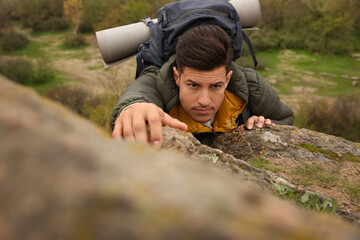 Wall Mural - Hiker with backpack climbing up mountain on autumn day