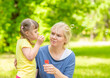 © Ermolaev Alexandr - Little girl with syndrome down blows bubbles in a summer park with her mother
