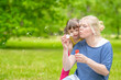 © Ermolaev Alexandr - Woman and little girl with syndrome down blow bubbles in a summer park. Empty space for text