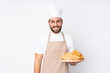 © luismolinero - Male baker holding a table with several breads isolated on white background laughing
