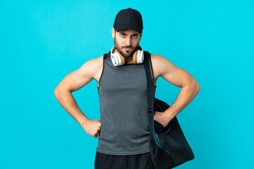 Wall Mural - Young sport man with sport bag isolated on blue background angry