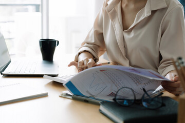 Close up Business woman or accountant using calculator with computer laptop, Business accounting, budget and loan paper at home