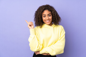 Young African American woman isolated on background happy and pointing up