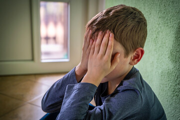 Poster - Trauriges junges Kind hält sich die Hände vor das Gesicht zum Thema familiäre Probleme oder Mobbing in der Schule