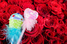 Blurred Background Of Red Roses And Focus On Pink Heart And Cupcake