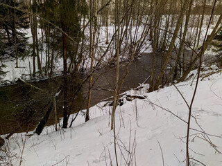 landscape of the river flow in the forest in early spring and snow view from the hill