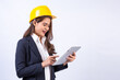 © Pituk - Confident architect Asian woman wearing black suit and yellow safety helmet using tablet computer standing isolated on gray background.