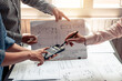 © amnaj - Architects meeting plan work using blueprints pointing at a calculator at the office.