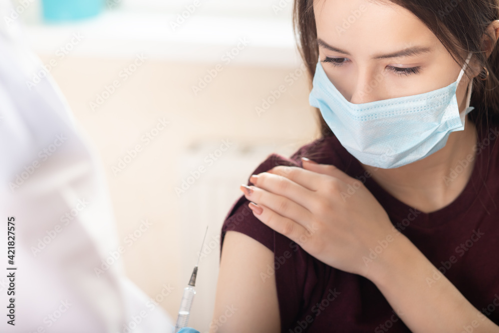 Doctor giving an injection of covid-19 vaccine to a teenage girl, protection against viruses and immunization - obrazy, fototapety, plakaty 