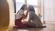 © Gorodenkoff - Shot of Happy Lesbian Couple Sitting on the Floor and Kissing at Home. Two Lovely Girls Spending Time Together, Enjoying Sunny Day. Authentic Tender Moments between Lovely Girlfriends.
