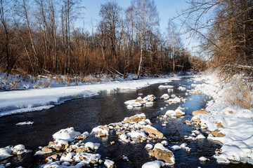 Sunny spring weather melts the ice on the river. the beauty of Russian nature. winter landscape. thawed the river. stones in the water are covered with snow. Sunshine morning