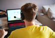 © garpinina - ragazzo con maglietta gialla che gioca con videogames su pc con cuffie e microfono