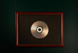 © sergeyyrev - Silver CD in a wooden photo frame on a dark background. Symbolic award.