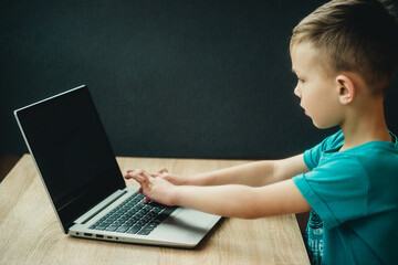 the boy is studying at the computer on a dark background